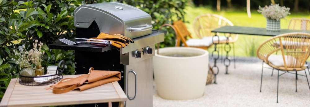 Grill auf Terrasse mit Gartenmöbeln